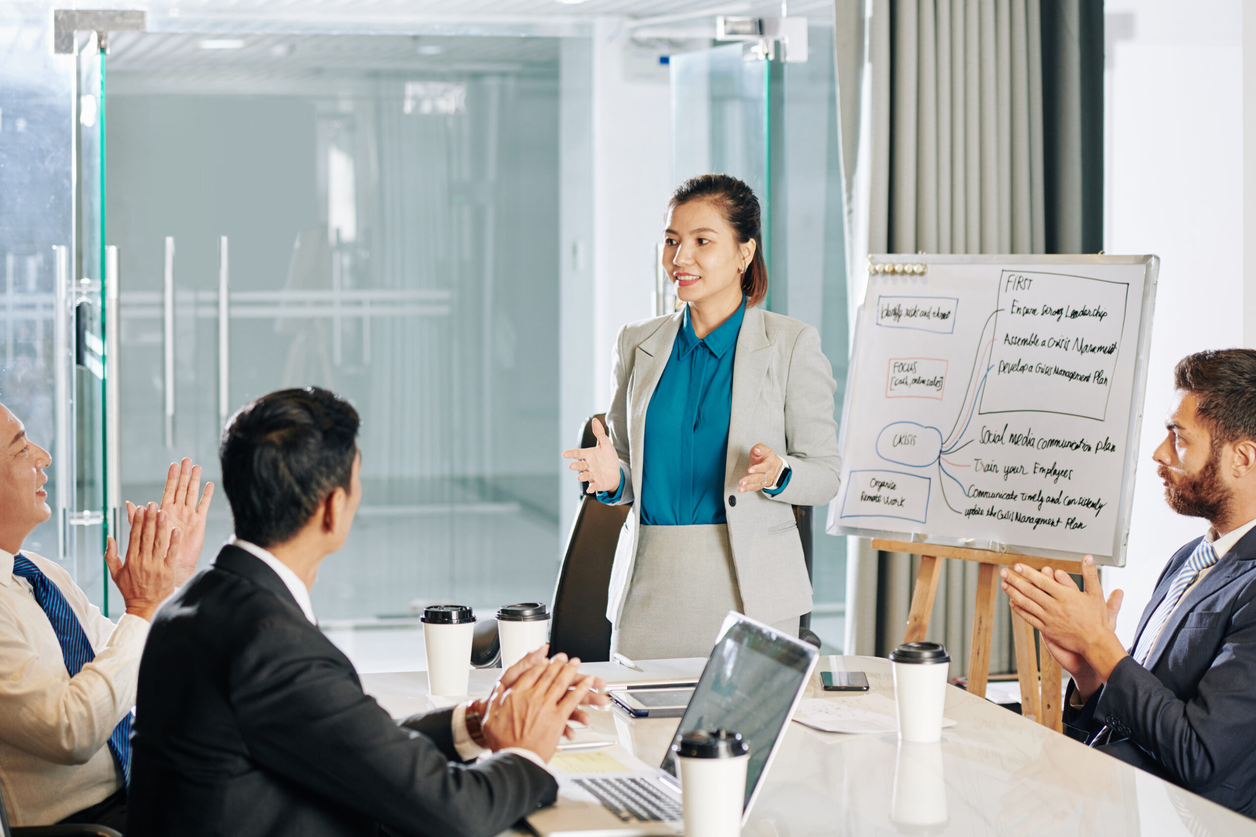 A confident professional delivers a sales pitch to a team, earning applause after presenting.