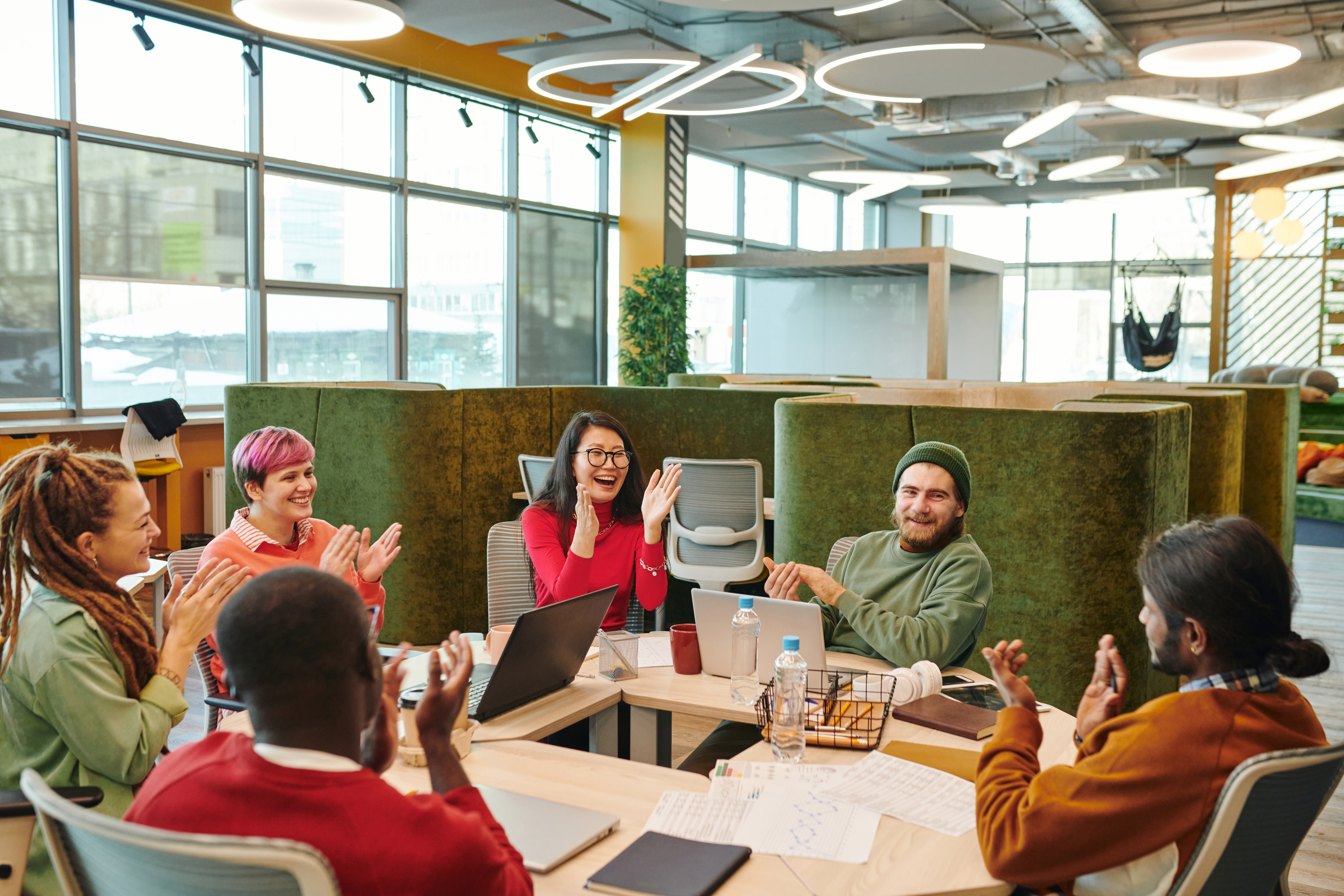Team members celebrate a win around a shared workspace, reflecting a positive work culture.