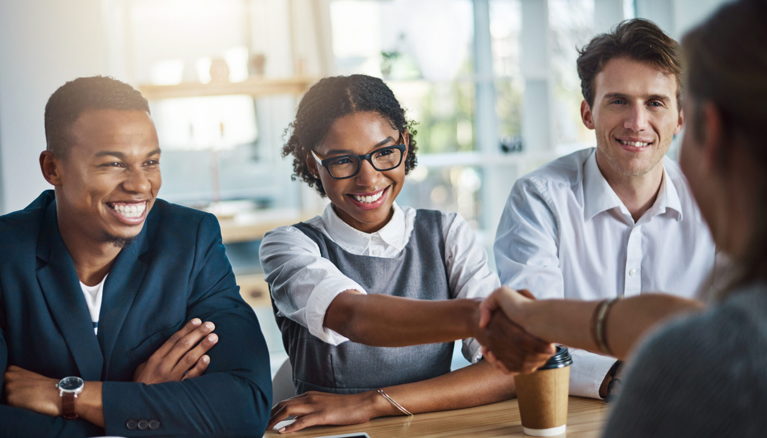 Young professionals shaking hands during a meeting about sales internships.