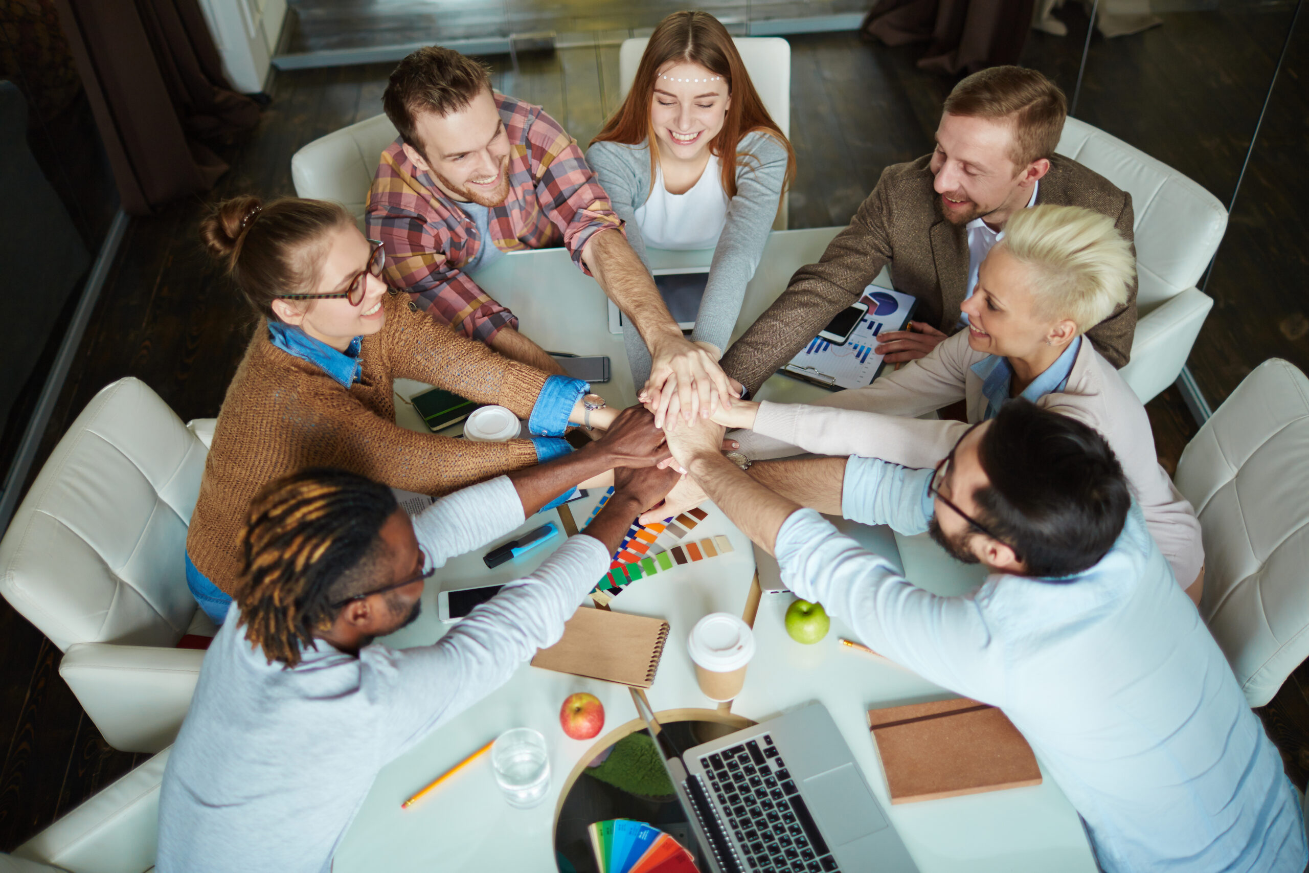 Employees stacking hands to showcase teamwork and positive team culture.